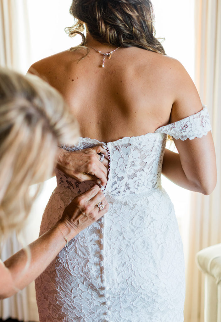 Mom zipping up wedding dress